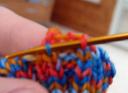 link up by bringing the sewing needle out through the very first knit stitch